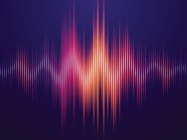 Colorful soundwave with bright orange, pink, and purple vertical bars on a dark purple background, illustrating audio or music frequency visualization.